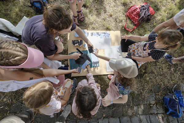 Fnf Kinder und eine Frau sind von Oben beim Gestalten zu sehen.